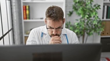 Yakışıklı bir İspanyol asıllı genç adam, bir doktor, kliniğinde oturuyor, bilgisayarla tanı üzerinde çalışıyor, kendini hasta hissederken, öksürürken, griple savaşırken. İç mekan portresi onun ciddiyetini yansıtıyor..