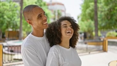 Güzel bir çift, neşe ve kahkaha ile dolular, kendine güvenle duruyorlar, sarılıyorlar ve parktaki gökyüzüne gülücüklerle bakıyorlar.