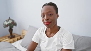 Şişt! Güzel Afro-Amerikalı kadın rahat yatak odasında sessizliğini koruyor, parmakları dudaklarında, sessiz ve gizli bir işaret veriyor.