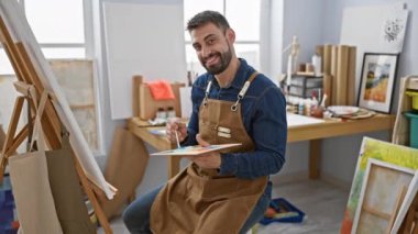 Kendine güvenen mutlu İspanyol genç adam, sanat stüdyolarında çalışan ressam. 