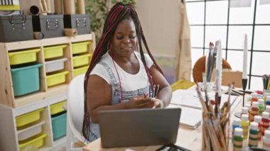 Kendine güvenen Afro-Amerikalı güzel örgülü kadın sanatçı, kapalı mekândaki stüdyosundan gelen bir video mesajı üzerine tutkulu bir sanat dersi sırasında tuvalini ve renkli kalemlerini birbirine bağlıyor.