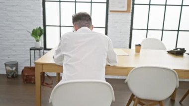 Neşeli, genç, İspanyol bir iş adamı. Ofis masasında sırıtarak arkasını dönüp gidiyor.