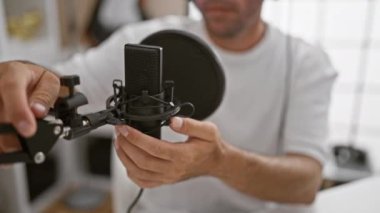 Çekici genç İspanyol erkek yayıncı, radyo stüdyosunda etkileyici bir şekilde konuşuyor.