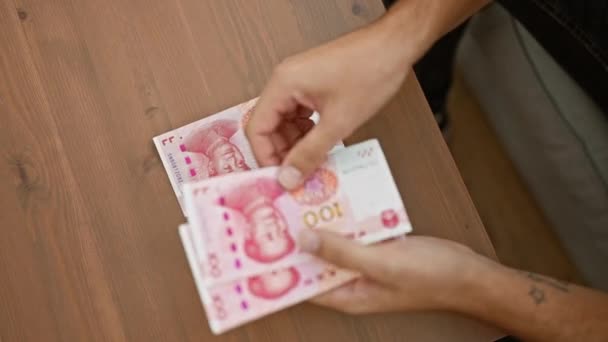 室内快照 充满活力的年轻人把钱算进去 舒舒服服地坐在家里的沙发上 银行富饶的人民币钞票窥视着中国经济 — 图库视频影像