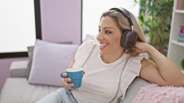 年轻的金发女人在家里听音乐喝咖啡 — 图库视频影像