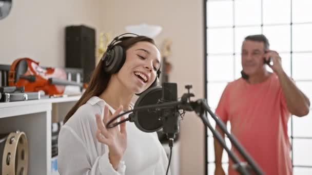 ヒスパニック系の男性と女性のミュージシャンに自信を持って 屋内ミュージックスタジオで音響的に歌い マイクのサウンドを介して — ストック動画