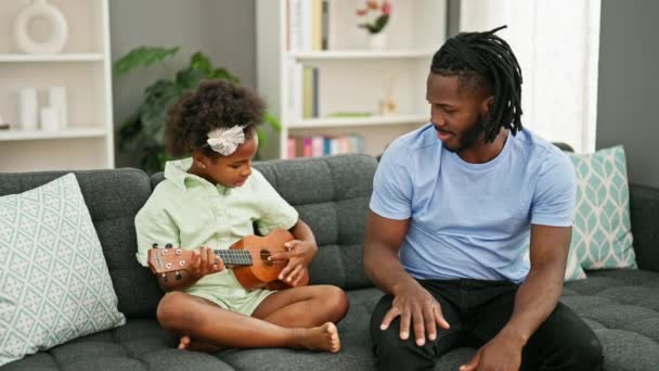 Африканский Американец Отец Дочь Сидят Диване Учат Играть Укулеле Дома — стоковое видео