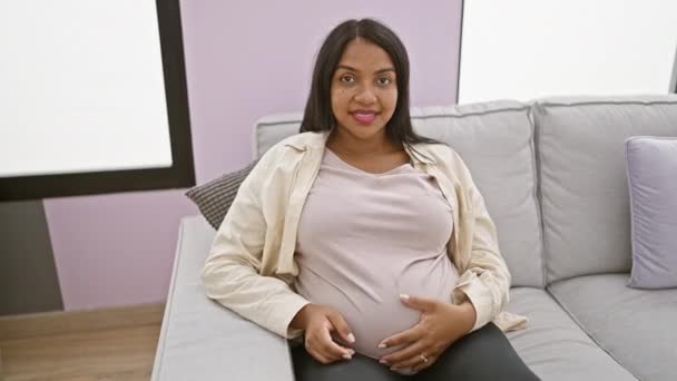 年轻的孕妇摸着肚子做着强有力的手势 胳膊在家里笑着 — 图库视频影像