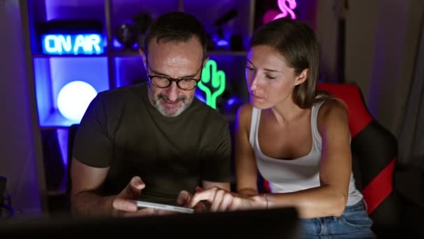 两个游戏玩家 一个是父亲 一个是女儿 一边从家里的游戏室里流淌着 一边高兴地学习智能手机游戏的艺术 — 图库视频影像