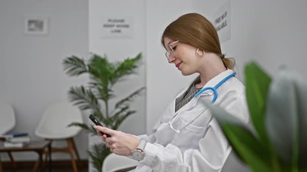 Joven Doctora Rubia Usando Smartphone Sentada Silla Sala Espera Clínica — Vídeos de Stock