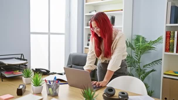 自信的红头发女商人在办公室的办公桌前庆祝工作的成功 快乐的年轻经理在笔记本电脑前得意地摆出成功的手势 — 图库视频影像