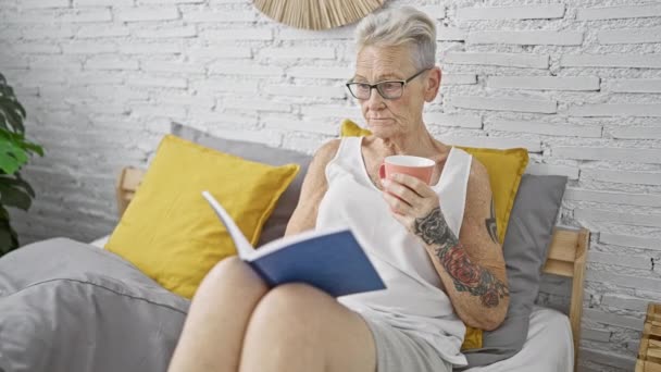 Ηλικιωμένη Γκριζομάλλα Γυναίκα Που Πίνει Καφέ Διαβάζοντας Βιβλίο Στο Υπνοδωμάτιο — Αρχείο Βίντεο