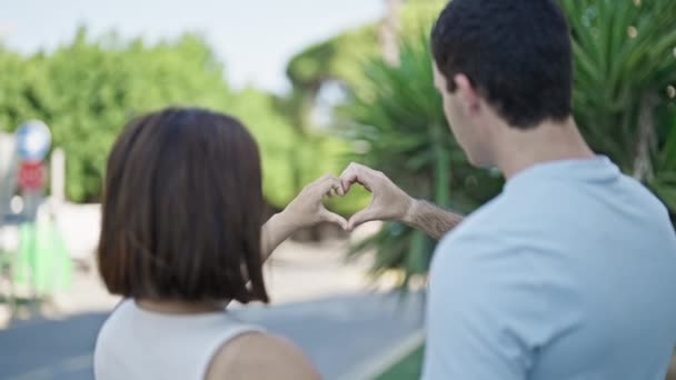 美丽的一对恋人微笑着 自信地用手在公园里做着心形 — 图库视频影像