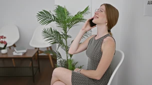 Junge Blonde Frau Sitzt Auf Stuhl Und Lächelt Auf Smartphone — Stockvideo