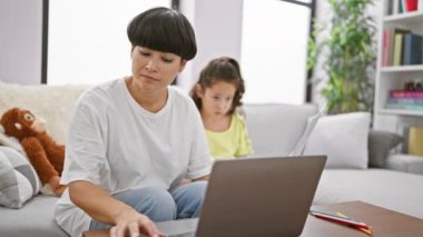 Anne ve kızının iç açıcı çalışma oturumu, rahat koltuklarında birlikte oturup, tele-çalışma ve ev ödevlerine dalmak, evde güzel bir aile anı yaratmak..