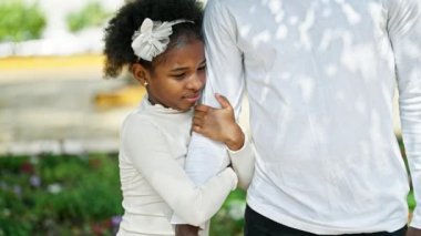 Afro-Amerikan baba ve kızı gülümsüyor. Parkta el ele tutuşuyorlar.