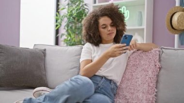 Güzel bir çift gülümsüyor, evdeki kanepede birlikte oturuyorlar- sabah kahvelerinin keyfini çıkarırken havaya duydukları sevgi ve güven, akıllı telefonlarında mesajlaşma