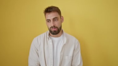 Sersemlemiş genç İspanyol bir adam saate bakıyor, sarı arka planda izole edilmiş sürpriz bir geri sayım zamanlayıcısının portresi.!