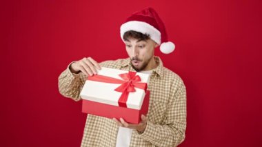 Kırmızı arka planda Noel Baba şapkalı yakışıklı genç adam.