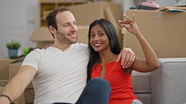 美しいカップルが床に座って一緒に新しい家で鍵を握る — ストック動画