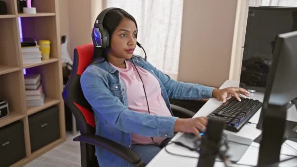 若いヒスパニック系女性ストリーマーが激しいビデオゲームをしながら母性を受け入れることを期待し 夜のホームゲームルームで腹を気遣う — ストック動画