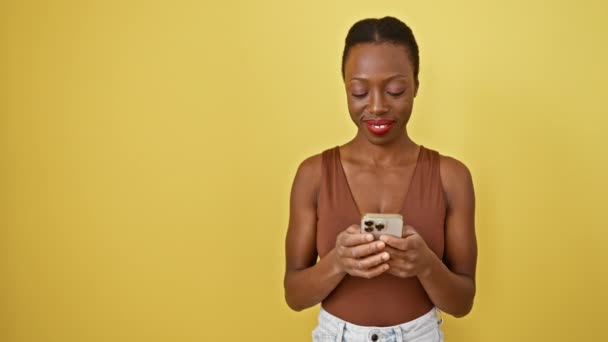 즐거운 아프리카계 미국인 한쪽을 가리키는 자신감으로 노란색 배경에 그녀의 전화를 — 비디오