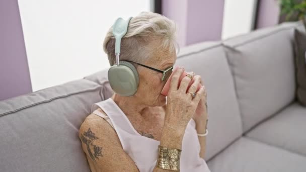 Feliz Anciana Pelo Gris Sentada Con Confianza Sofá Casa Escuchando — Vídeo de stock