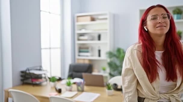 严肃的红头发女商人 在办公室边走边工作 在室内工作氛围中 有疑问但成功的老板思维 耳机对曲调的支持 — 图库视频影像