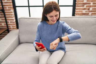 Evde akıllı telefon kullanan genç sarışın kadın.