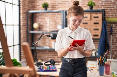 Young blonde woman artist smiling confident drawing on touchpad at art studio