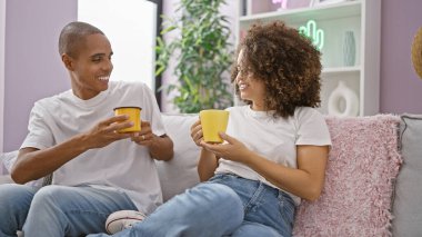 Kendine güvenen, güzel bir çift, evlerinde rahat bir hayat sürmekten hoşlanırlar. Neşeyle gülümsediler, oturma odalarında kanepede oturdular espresso içtiler, sevgi ve mutlulukla doluydular..