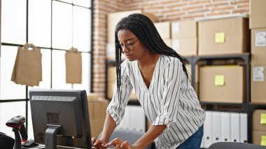 Ofiste duran bilgisayarı kullanan Afrikalı Amerikalı kadın ecommerce işçisi.