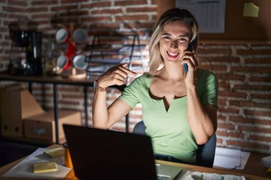 Geceleri ofiste çalışan genç ve güzel bir kadın telefonda konuşuyor. Kendine güveni tam görünüyor. Kendini gururlu ve mutlu bir şekilde gösteriyor.. 