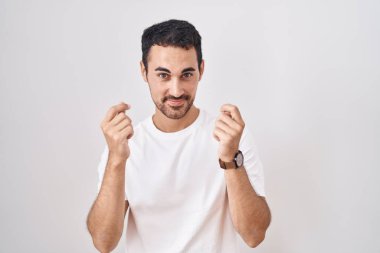 Beyaz arka planda duran yakışıklı İspanyol adam elleriyle para hareketi yapıyor, maaş istiyor, milyonerlik işi yapıyor. 