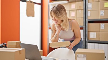 Genç sarışın iş kadını ofiste dizüstü bilgisayar paketi kullanıyor.