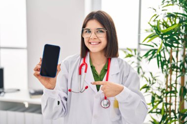 Genç İspanyol doktor kadın akıllı telefon ekranı gösteriyor. Gülümseyen mutlu ve gururlu birini işaret ediyor. 