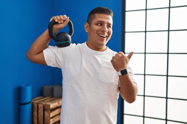 Dambıl kullanan İspanyol genç adam baş parmağını yana doğru uzatıyor ve ağzı açık gülümsüyor. 