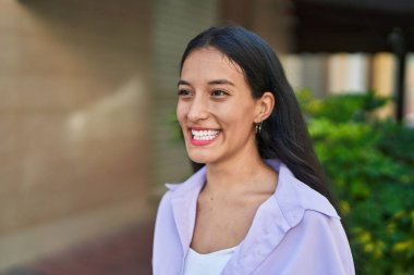 Young beautiful hispanic woman smiling confident looking to the side at street