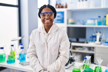 Yüzünde mutlu ve havalı bir gülümsemeyle bilim adamı laboratuvarında çalışan Afrikalı Amerikalı bir kadın. şanslı kişi. 