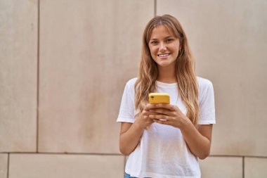 Young blonde girl smiling confident using smartphone over white isolated background