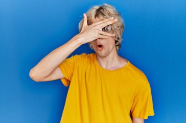 Genç modern bir adam mavi arka planda dikiliyor. Şoka giriyor. Yüzü ve gözleri kapanıyor.. 