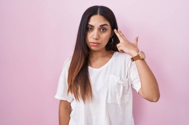 Pembe arka planda duran genç Arap kadın kendini ve parmaklarını silah gibi havaya kaldırarak vuruyor, intihar ediyor.. 