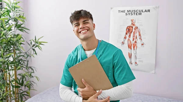 一个年轻英俊的恐慌男子的画像 他是康复诊所的治疗师 在做治疗笔记的时候带着自信的微笑 — 图库照片
