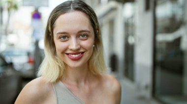 Sokakta kendine güvenen genç sarışın kadın gülümsüyor