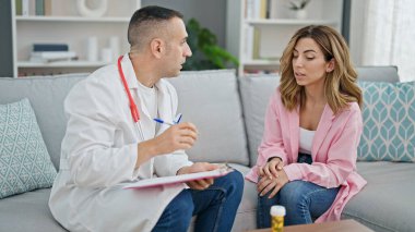 Kadın, erkek, doktor ve hasta klinikte sağlık raporu yazıyor.