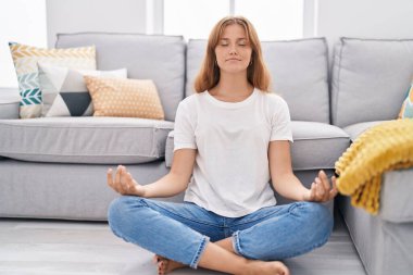 Genç sarışın kız yoga egzersizi yapıyor evde oturuyor.