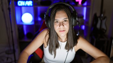 Genç, İspanyol asıllı, güzel bir kadın. Oyun salonunda ciddi bir yüzle masada oturuyor.