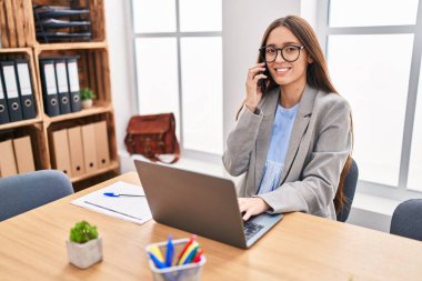 Genç, güzel İspanyol iş kadını. Ofiste bilgisayarla konuşuyor.