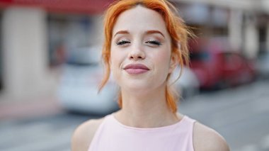 Caddede kendine güvenen genç kızıl saçlı kadın gülümsüyor