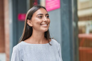 Young beautiful hispanic woman smiling confident looking to the side at street